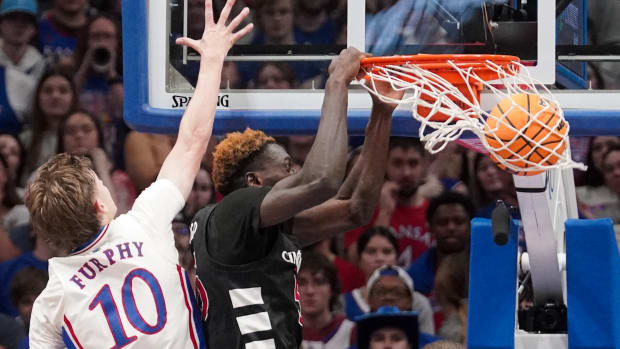 Jan 22, 2024; Lawrence, Kansas, USA; Cincinnati Bearcats forward Aziz Bandaogo (55) dunks the ball as Kansas Jayhawks guard Johnny Furphy (10) defends during the second half at Allen Fieldhouse. Mandatory Credit: Denny Medley-USA TODAY Sports